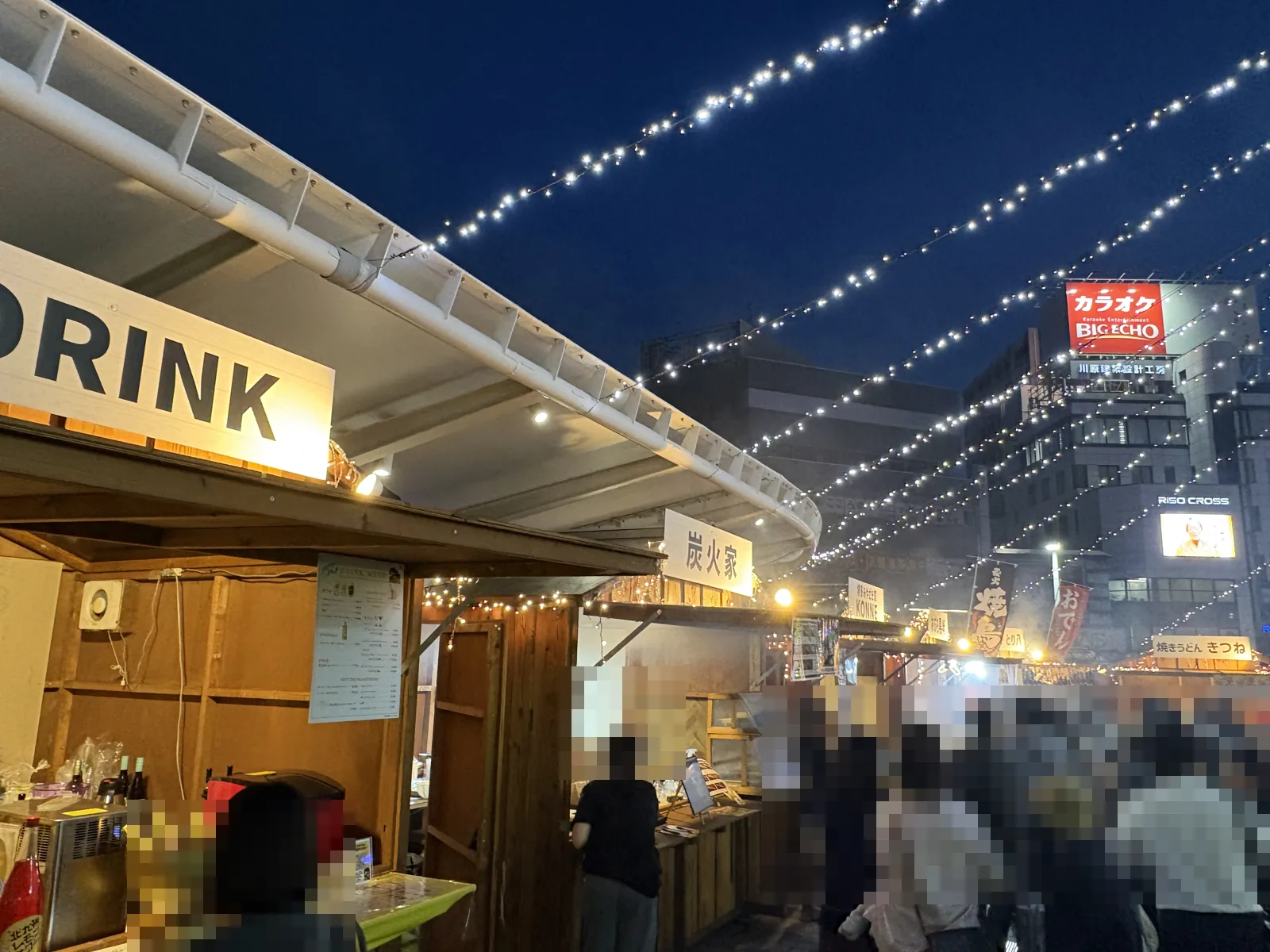 DRINKと炭火家の屋台の前に人の列ができ、奥から煙が上がる
