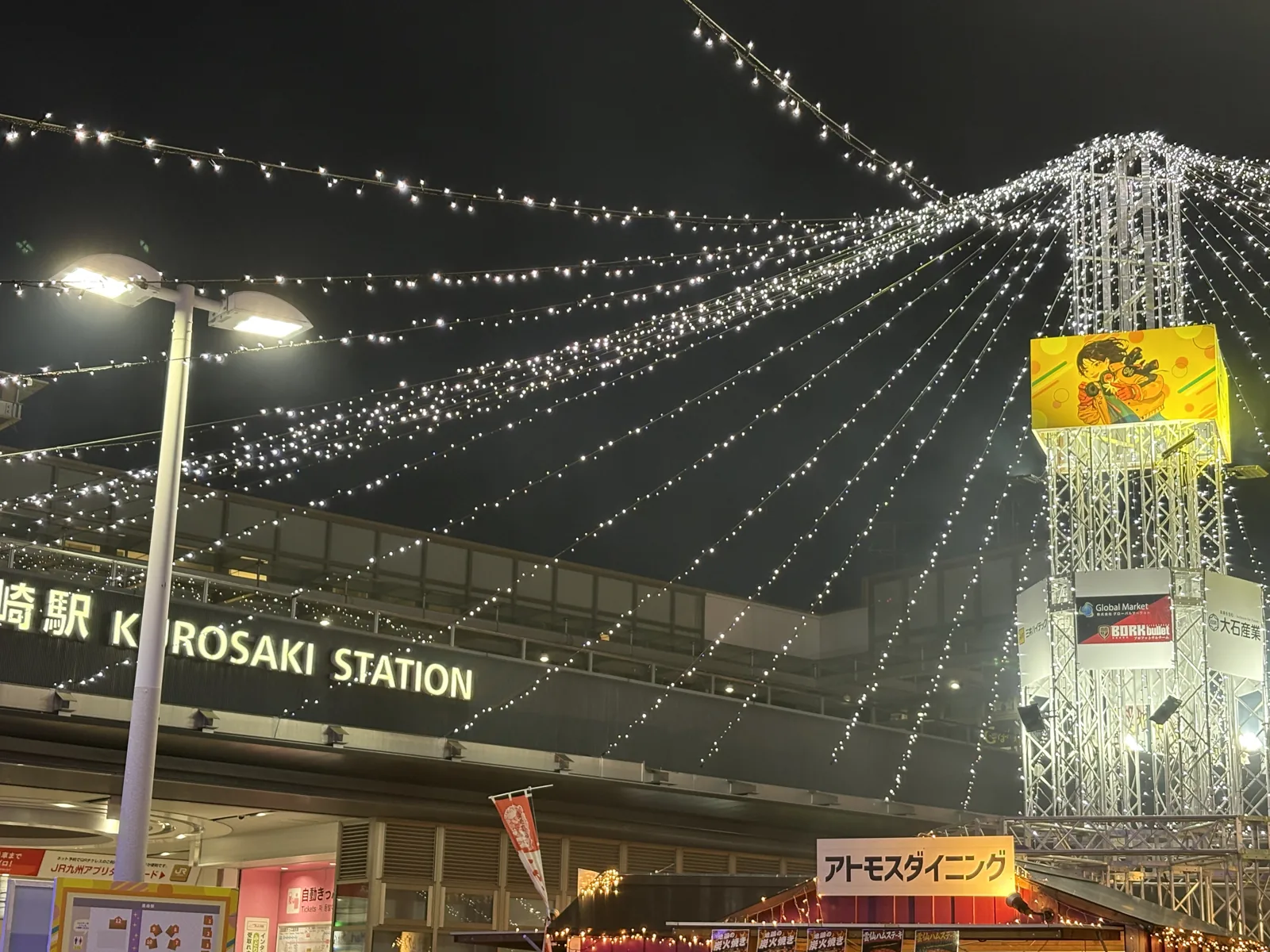 黒崎駅の駅名看板の前で、タワーから放射状に伸びるイルミネーションが光る