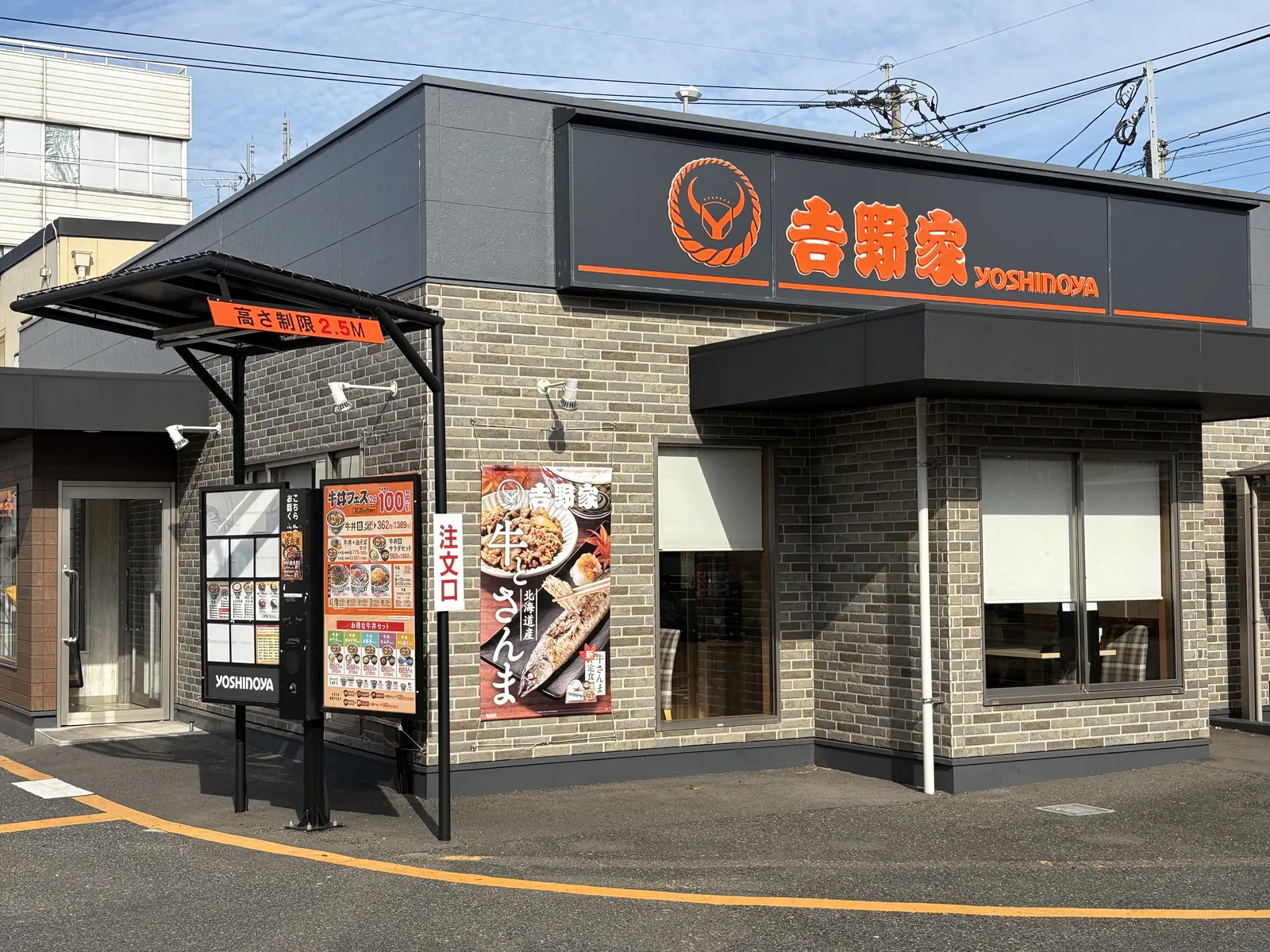黒い外壁に吉野家のオレンジ文字。壁に「北海道産 牛とさんま」のポスター